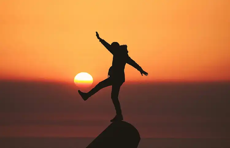 Photo of silhouette photo of man standing on rock